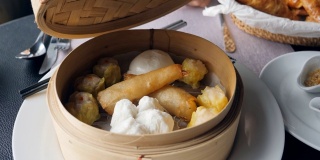 年轻女子打开篮子里的饺子放在桌上点心，传统的中国饺子在传统的木篮子里