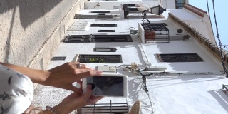 垂直视频的游客卷曲的黑发拍照在白色的村庄Altea，阿利坎特，西班牙