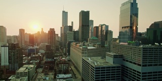 无人机飞过芝加哥河，太阳在市中心建筑后升起
