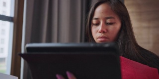 多病的年轻女子躺在沙发上，拿着平板电脑。有喉咙痛