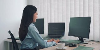亚洲女性软件开发人员正在一起分析编写到办公室电脑上的程序的代码。