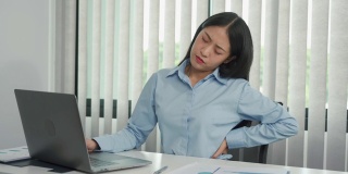 亚洲女性长时间坐着工作，按摩双手时会背痛。