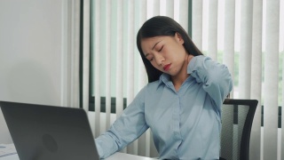 一位年轻的亚洲女性正坐在公司的办公室里，脖子很疼。视频素材模板下载