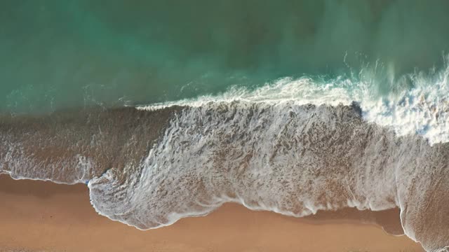 金沙海浪和绿松石海水与白色泡沫从小海浪风景鸟瞰图。暑假的概念。明亮的抽象背景适合任何设计。无人机的幻灯片