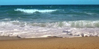 阳光明媚的日子里奔跑的海浪慢镜头。风暴在海面上。水和沙子的质地。海岸。明亮的金色的沙子。大浪冲击着沙滩。金色的沙滩上泛着白色的浪花