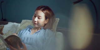 一个亚洲女人在酒店卧室的床上看书