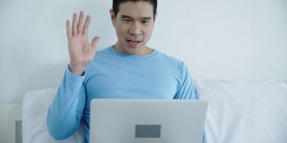 快乐的亚洲人使用笔记本电脑或笔记本电脑在房间在家里工作。通过在线聊天和同事聊天。使用通讯技术的生活方式和工作方式。家庭概念工作