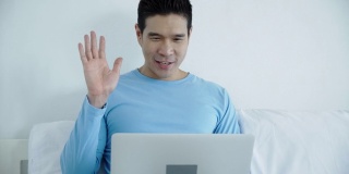 快乐的亚洲人使用笔记本电脑或笔记本电脑在房间在家里工作。通过在线聊天和同事聊天。使用通讯技术的生活方式和工作方式。家庭概念工作