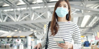 新冠肺炎后的旅行:戴口罩的妇女在机场候机楼检查航班