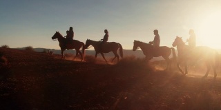 在夏季黄昏的纪念碑谷部落公园附近的沙漠里，纳瓦霍印第安人骑着他们的马