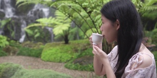 亚洲女孩在花园喝茶与复印空间