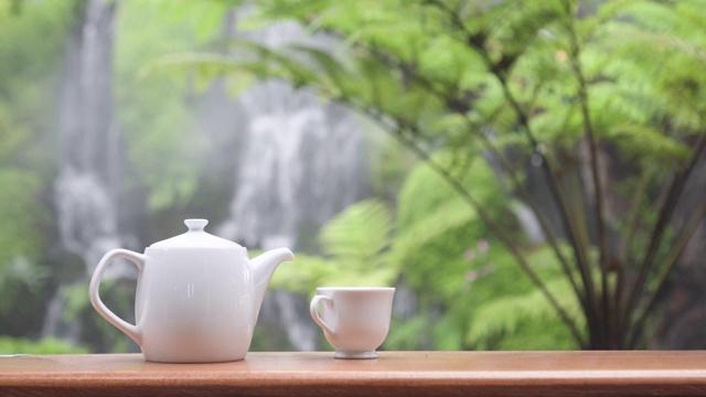 广角拍摄的静物茶具在花园与瀑布的背景