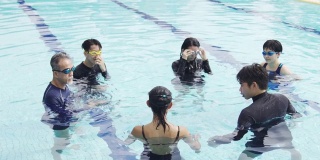亚洲华人游泳教练在游泳池里教他的学生做准备