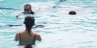 亚洲华人活跃的资深夫妇游泳运动员向教练在游泳池练习游泳