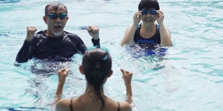 亚洲华人活跃的资深夫妇游泳运动员向教练在游泳池练习游泳