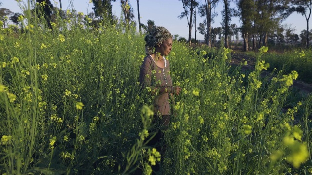 非洲黑人新兴女农民正在检查她在菜园里种的芥末菠菜的花