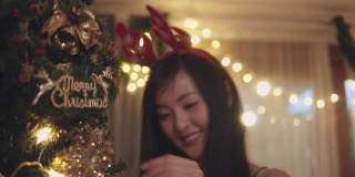快乐的女人在家里装饰圣诞树。