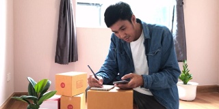 亚洲男子书写订单产品从客户电话订购他在记事本上记录准备货物或货物运送给客户在新冠肺炎新常态的日子