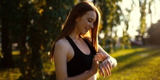 侧视图有吸引力的年轻女子运动员使用运动智能手表上的运动应用程序。
