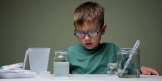 戴眼镜的男孩在室内用吸管和液体做化学实验。学习，有兴趣地学习。选择教育。研究背景。成功学习的个人素质