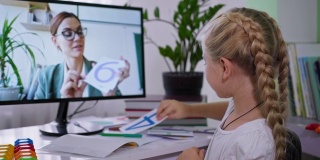 远程教学时，女孩在家里用电脑向女老师展示带数字的卡片