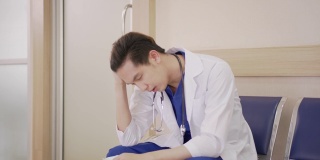 年轻的亚洲医生坐在医院走廊感觉疲倦，沮丧，悲伤，疲劳，问题，倦怠压力和不安或担心的工作。医疗职业概念中的过度工作或工作量。