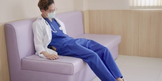 年轻的亚洲医生坐在医院走廊感觉疲倦，沮丧，悲伤，疲劳，问题，倦怠压力和不安或担心的工作。医疗职业概念中的过度工作或工作量。