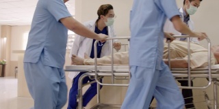 一组年轻的亚洲医生，护士和工作人员推担架在走廊走廊医院与昏迷病人在床上全设施在辅助医疗保健医疗概念。