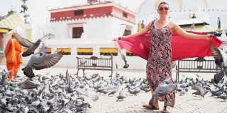 一名女子在尼泊尔加德满都东方广场中心旋转的慢动作视频，鸽子在慌乱中起飞