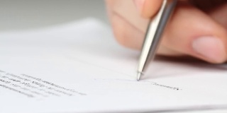 一个商人签署合同，法律协议或文件的特写镜头。人通过签署文件来批准文件。