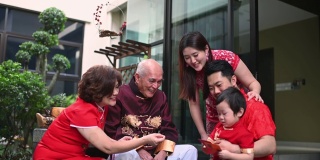 春节团圆饭后，亚洲华人家庭的老爷爷给孙子送红包红包，吃传统菜肴生鱼