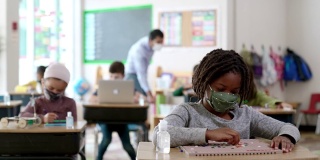 2019冠状病毒病期间，戴口罩的学生在教室里