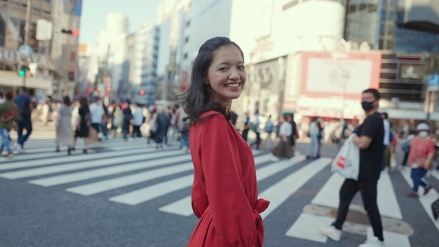 Young woman in red dress standing on Shibuya crossing, looking at camera