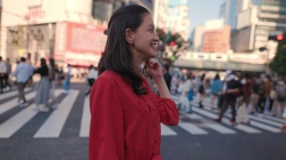 身着红裙的年轻女子站在涉谷十字路口，望着别处视频素材模板下载