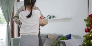 圣诞快乐，亚洲家庭团聚的概念。快乐的亚洲老人走进家门，在探望儿女家庭中享受给孙子送礼物的礼盒。