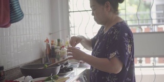 年长的亚洲妇女在家做饭。