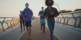 一群朋友早上跑步，脸上戴着防护面具，慢动作。冠状病毒保护的概念