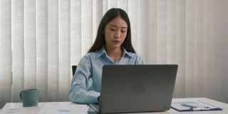 亚洲女性经理是压力和头痛错误的工作文件在她的办公室。