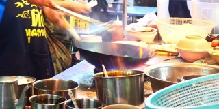 在泰国曼谷唐人街做街边小吃。在平底锅里炒面条，火和火焰下它