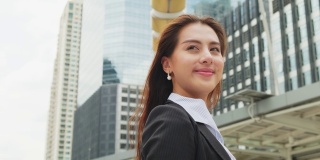 亚洲年轻聪明的女商人在城市的公司办公室工作。快乐自信的女孩微笑着站在户外。业务概念的职位申请和招聘。
