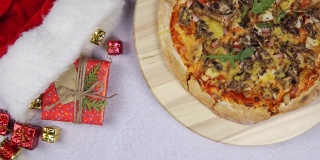 平铺的披萨在木托盘上360度旋转，围绕圣诞装饰