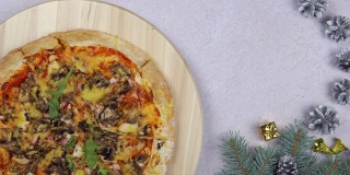 平铺的披萨在木托盘上360度旋转，围绕圣诞装饰