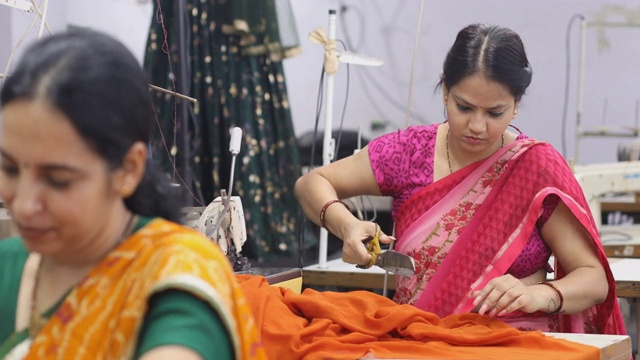 印度女工在生产线上裁剪服装面料