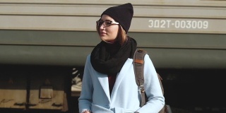 肖像女孩站在铁路月台与背包背景的火车。