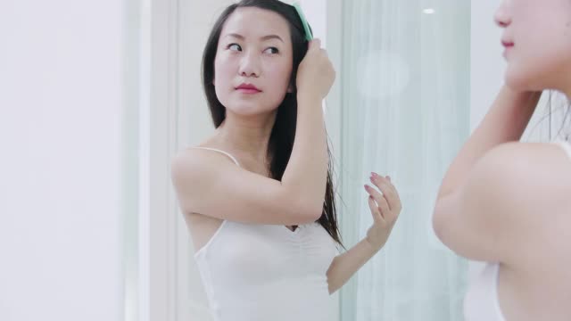 美丽的亚洲女人在家里洗澡后梳头