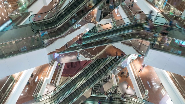 在大型现代化购物中心的自动扶梯上行走的顾客。
