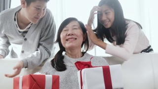 亚洲的孩子会给他们的母亲惊喜，并在母亲节或特别的活动概念送礼物盒给她。视频素材模板下载