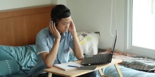 年轻的亚洲人在家里使用笔记本电脑学习
