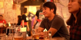 亚洲男子喜欢在居酒屋酒吧喝酒和听他的朋友开玩笑