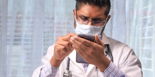医生戴着防护口罩在医院使用智能手机。